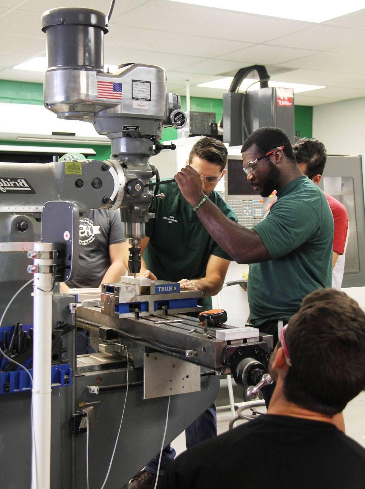 机械 engineer students working with engineering machinery.